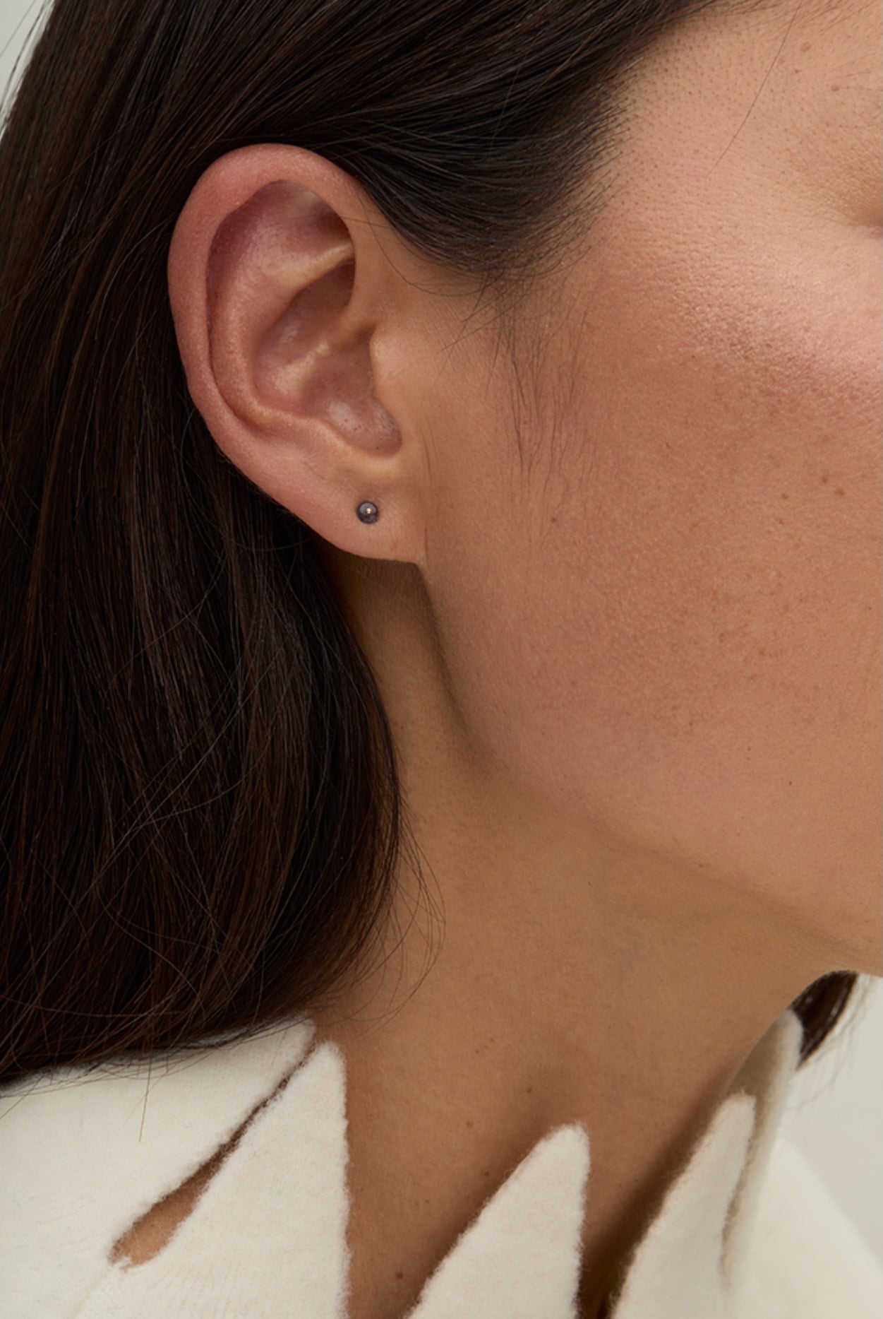 Model wearing delicate gold gemstone stud earrings styled for everyday layering.