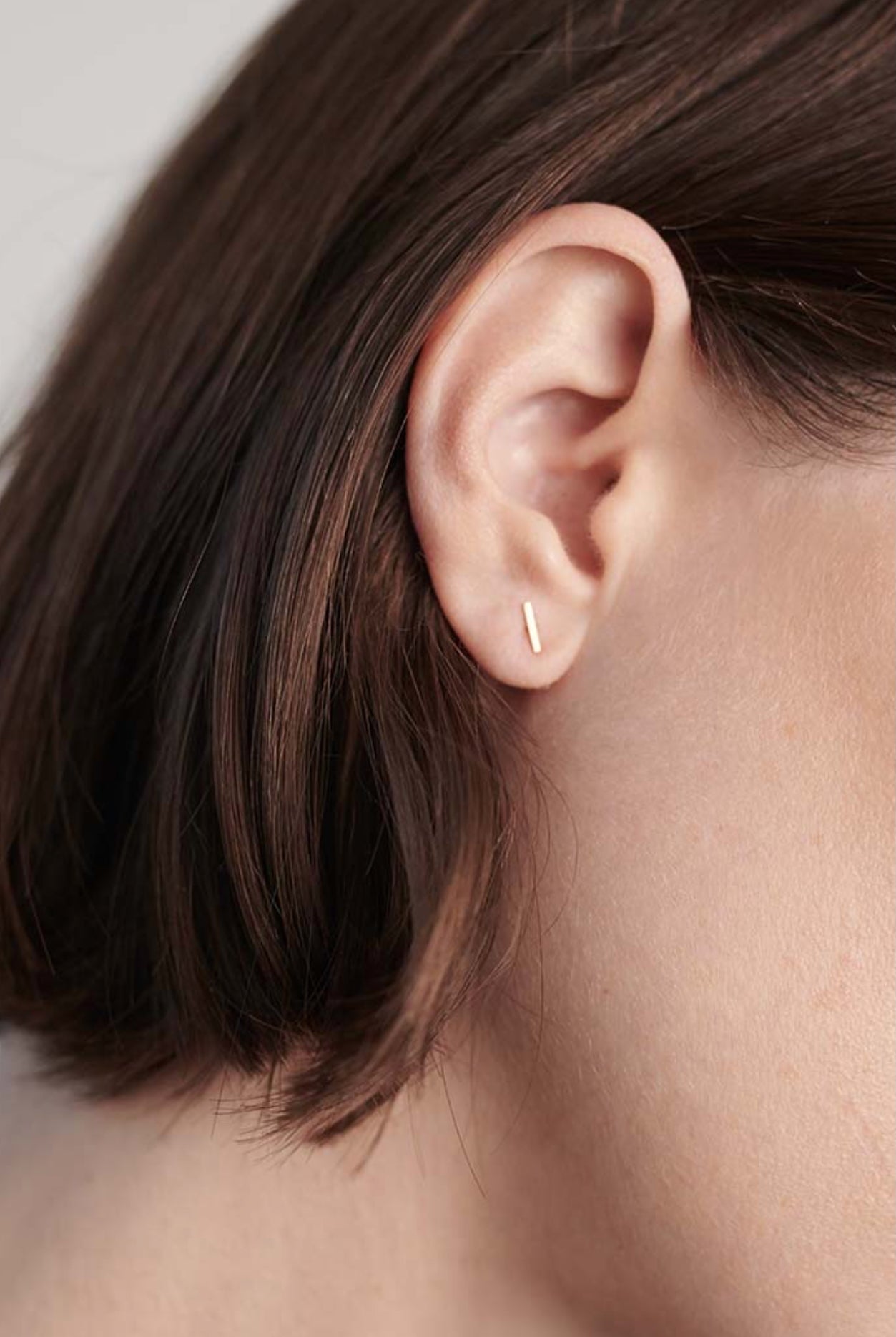 Model wearing 14K gold T-bar stud earring styled for everyday wear.