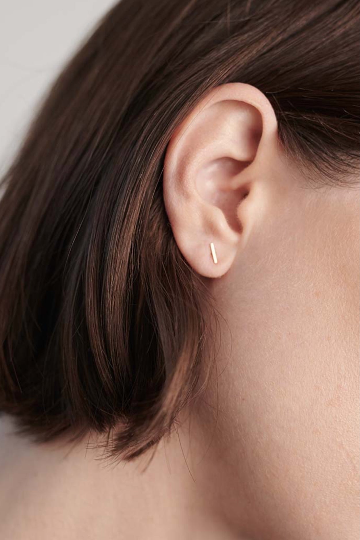 Model wearing 14K gold T-bar stud earring styled for everyday wear.