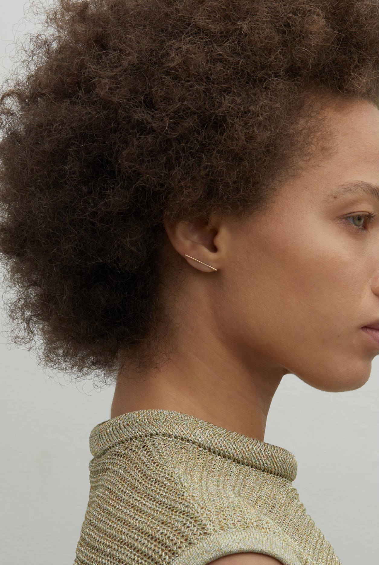 Model wearing delicate 14K gold long bar stud earring.