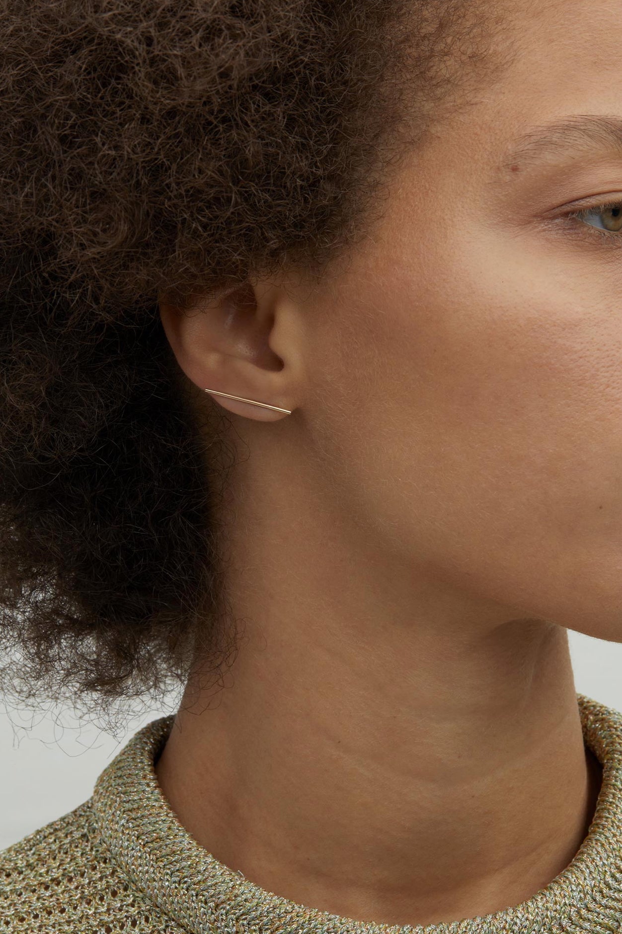 Model wearing 14K gold minimalist bar stud earrings.