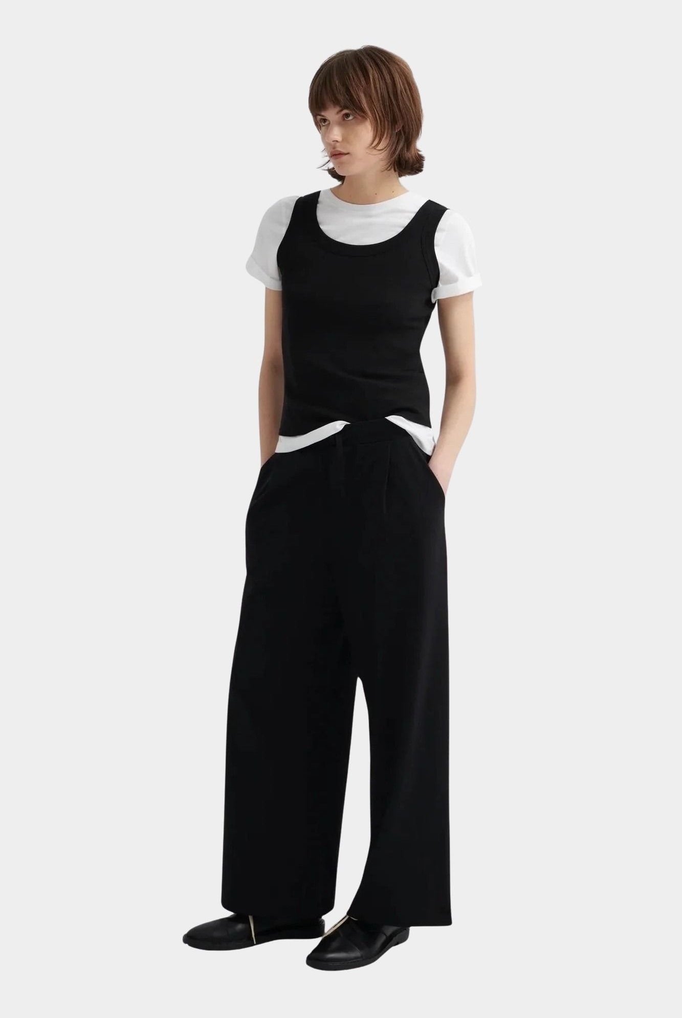 Kowtow Everyday Tank in black worn with wide leg black trousers, full length view