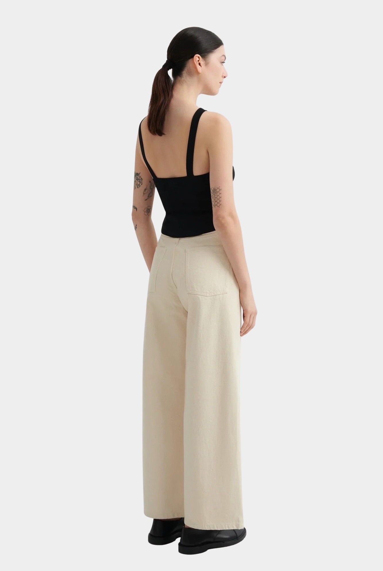 Kowtow Low Back Tank in black worn with cream wide leg trousers, back view