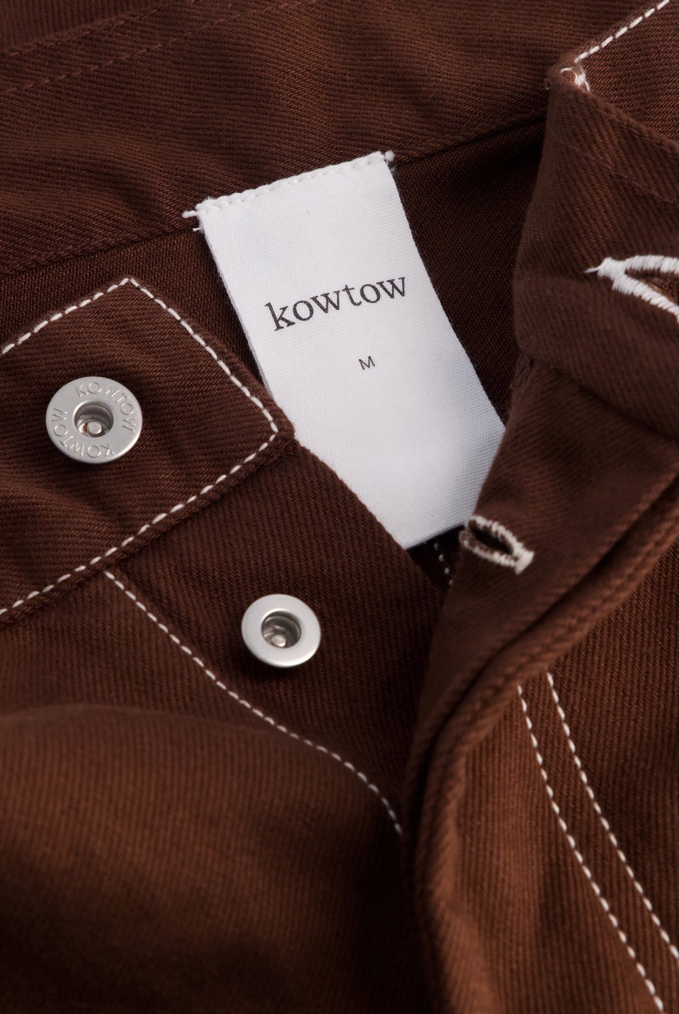 Kowtow Unity Jeans in brown denim close up interior label and metal button detail