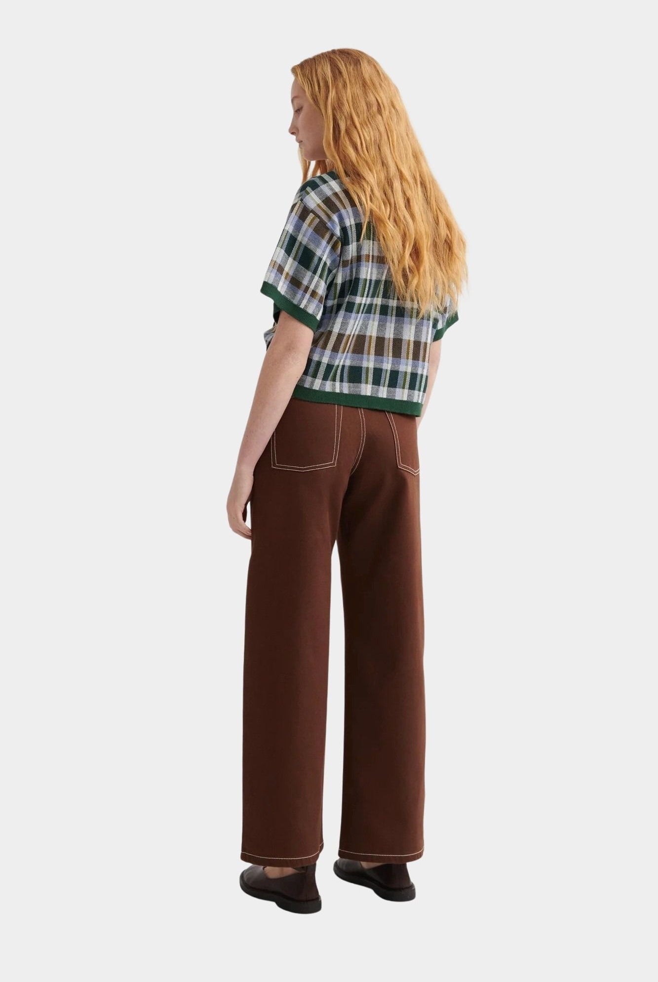 Kowtow Unity Jeans in brown denim worn with plaid knit top, full length back view