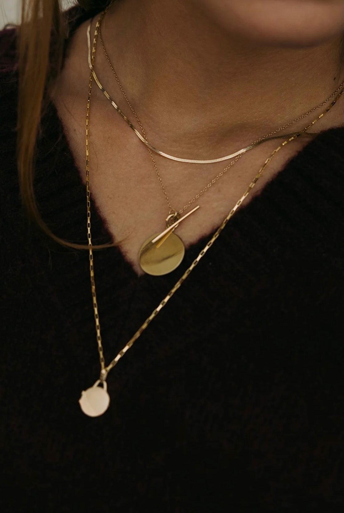 Model wearing 10K gold herringbone chain necklace layered with pendant.