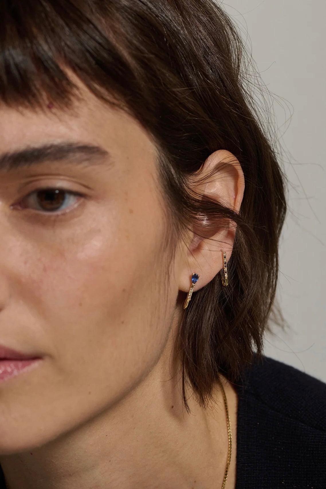 Model wearing 14K gold pear sapphire and diamond hoop earrings.