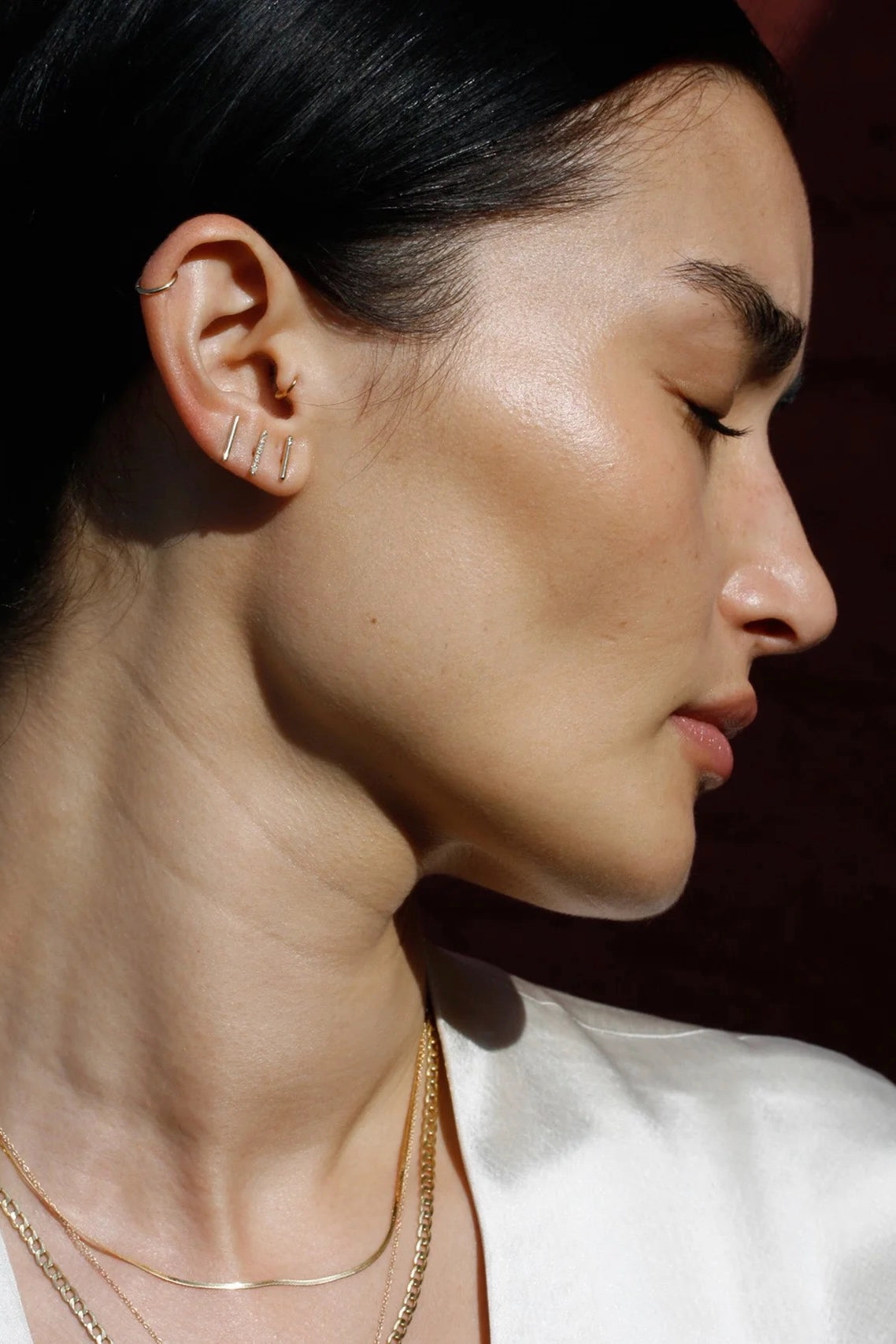Model wearing 14K gold vertical bar stud earrings.