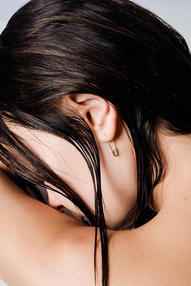 Model wearing 14K gold safety pin hoop earring.