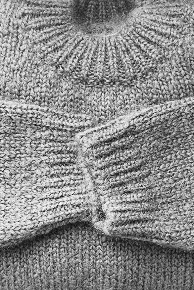 Close view of textured knit sweater with ribbed neckline and cuffs