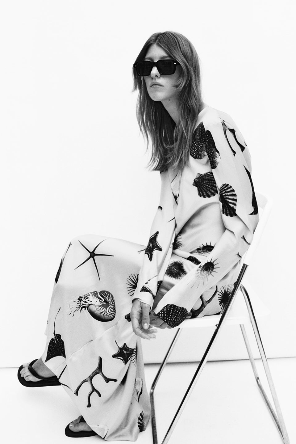 Woman wearing a flowing printed maxi dress seated on a chair