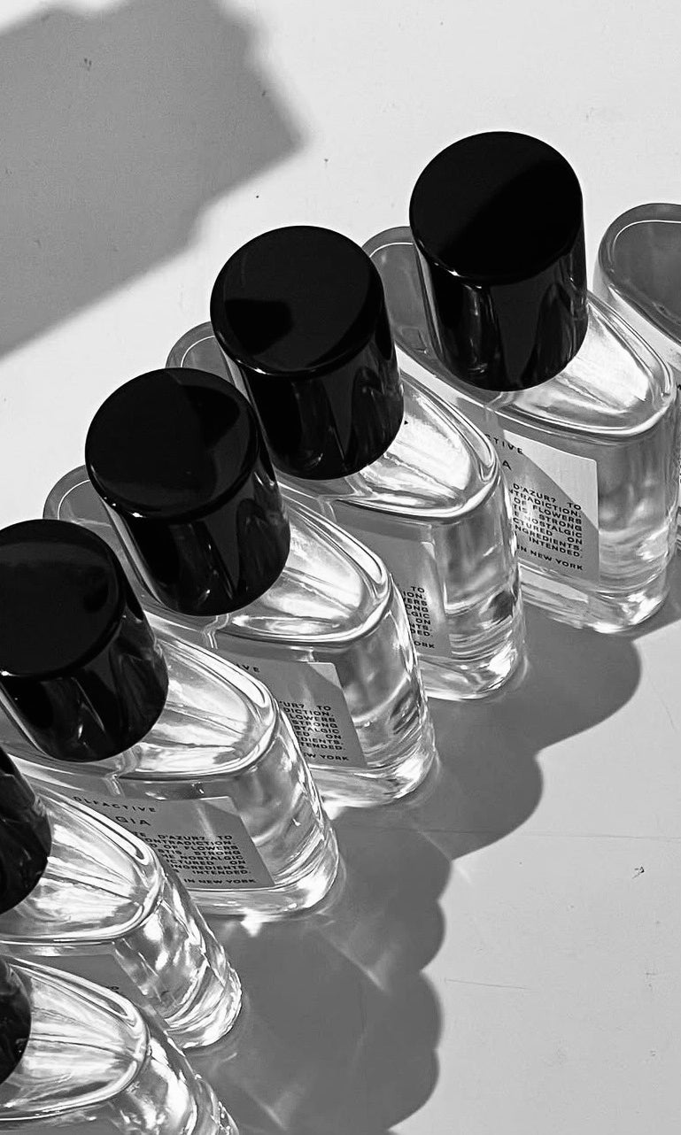 Black-and-white photo of perfume bottles with black caps arranged in a row