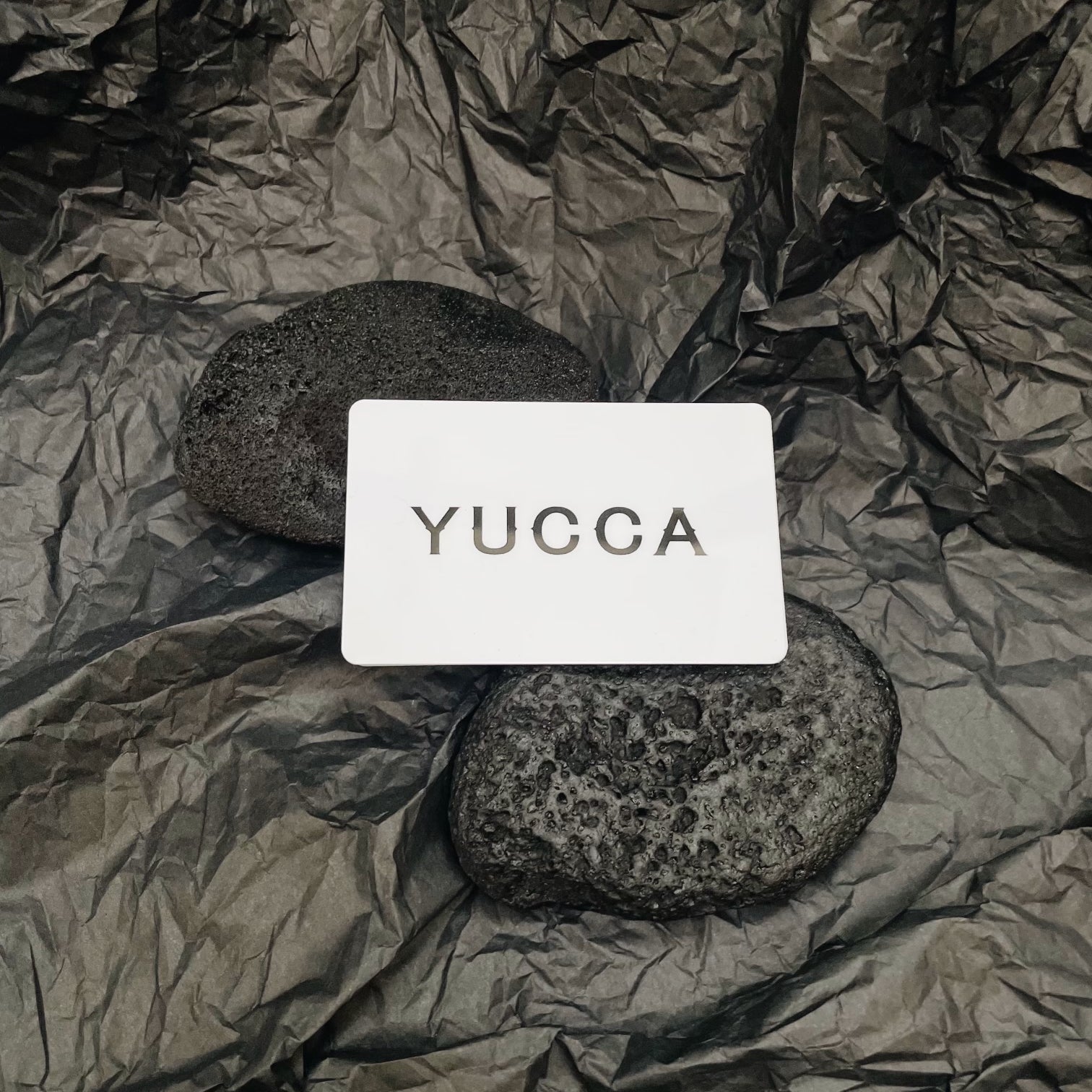YUCCA gift card displayed on textured paper with natural stones
