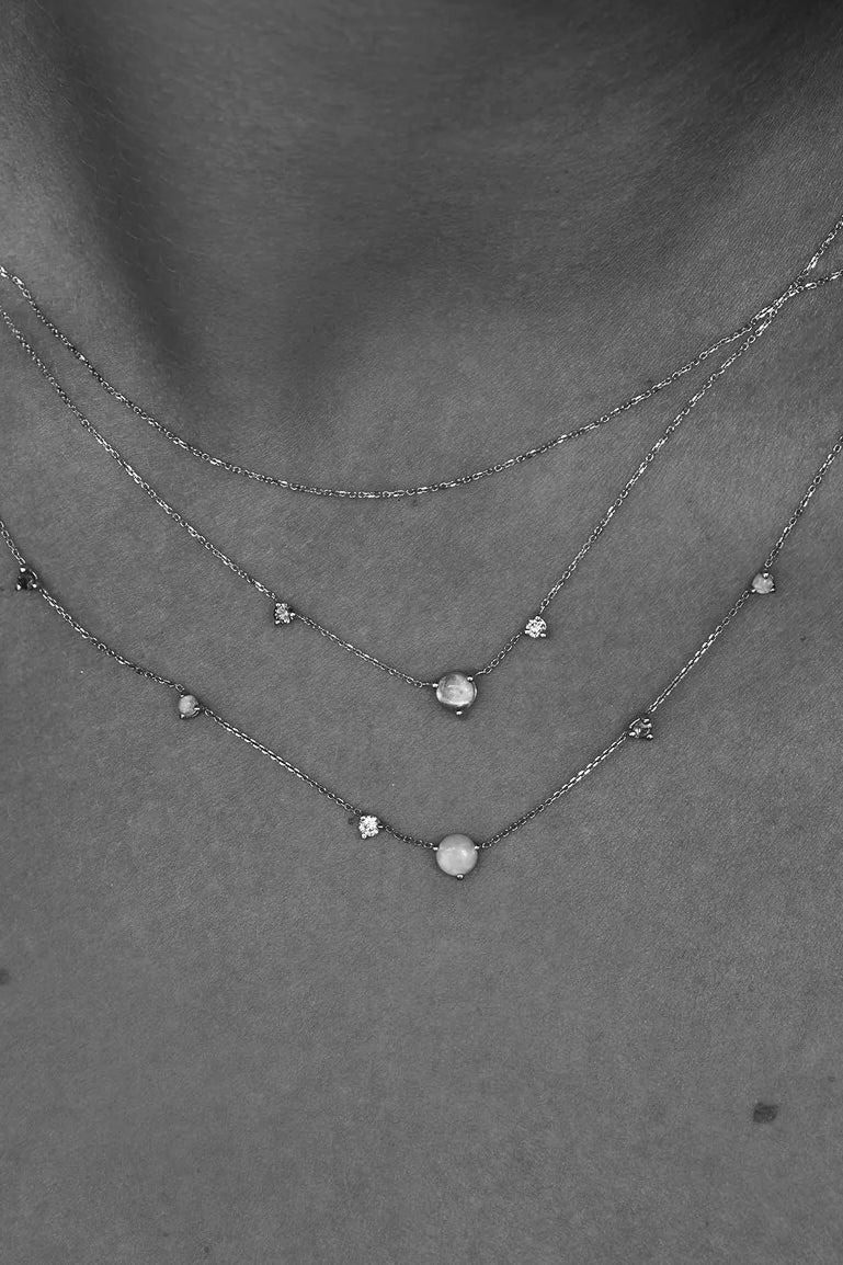 Layered fine gold necklaces with opal and diamond details on model, modern minimalist jewelry