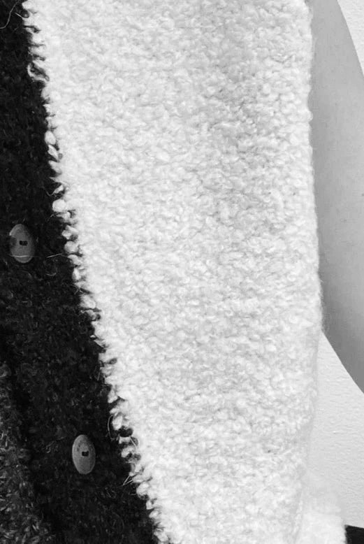 Close view of a textured two-tone knit top with button detail