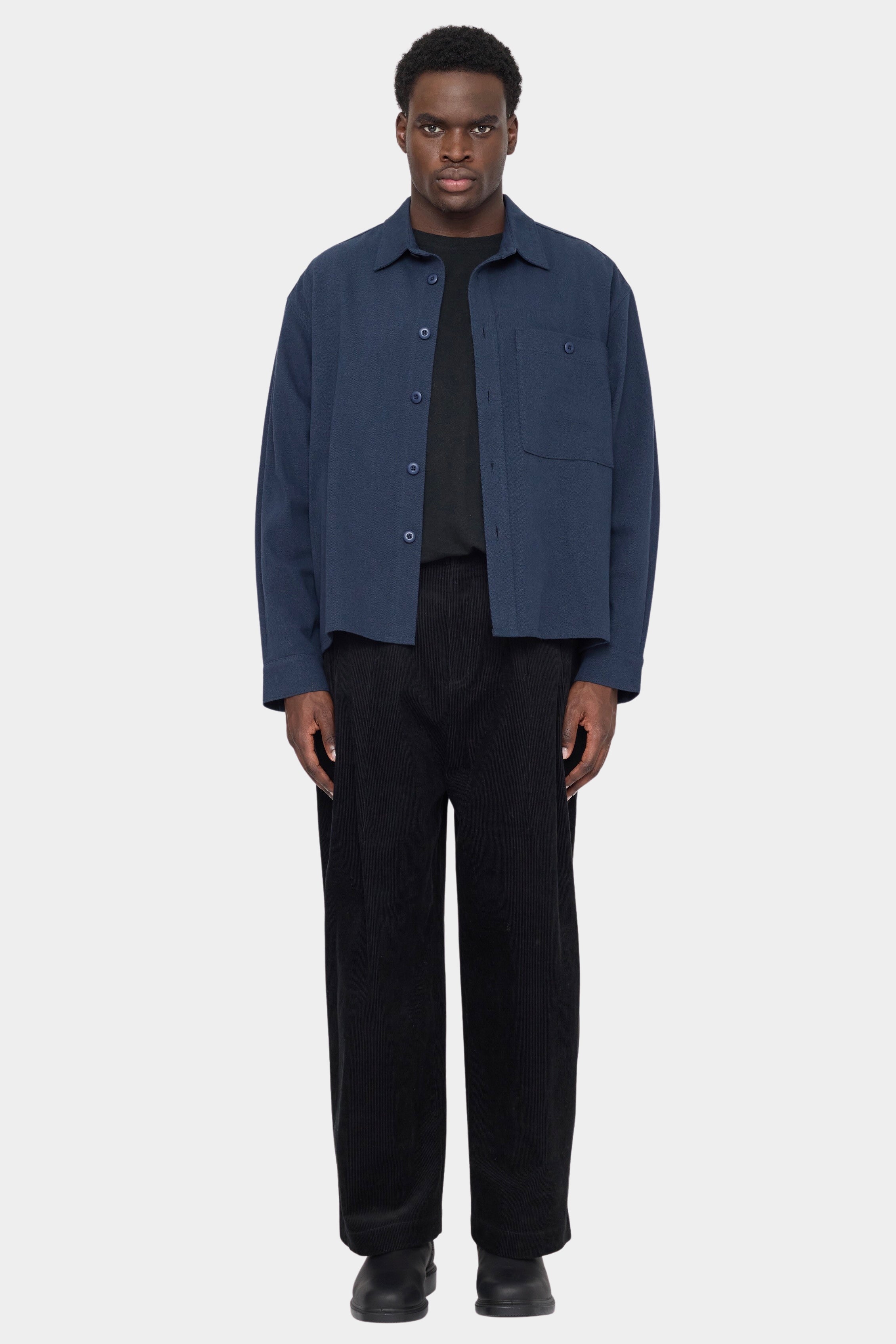 Front view of the navy 7115 by Szeki Relaxed Pocket Shirt worn open over a black tee at YUCCA Denver