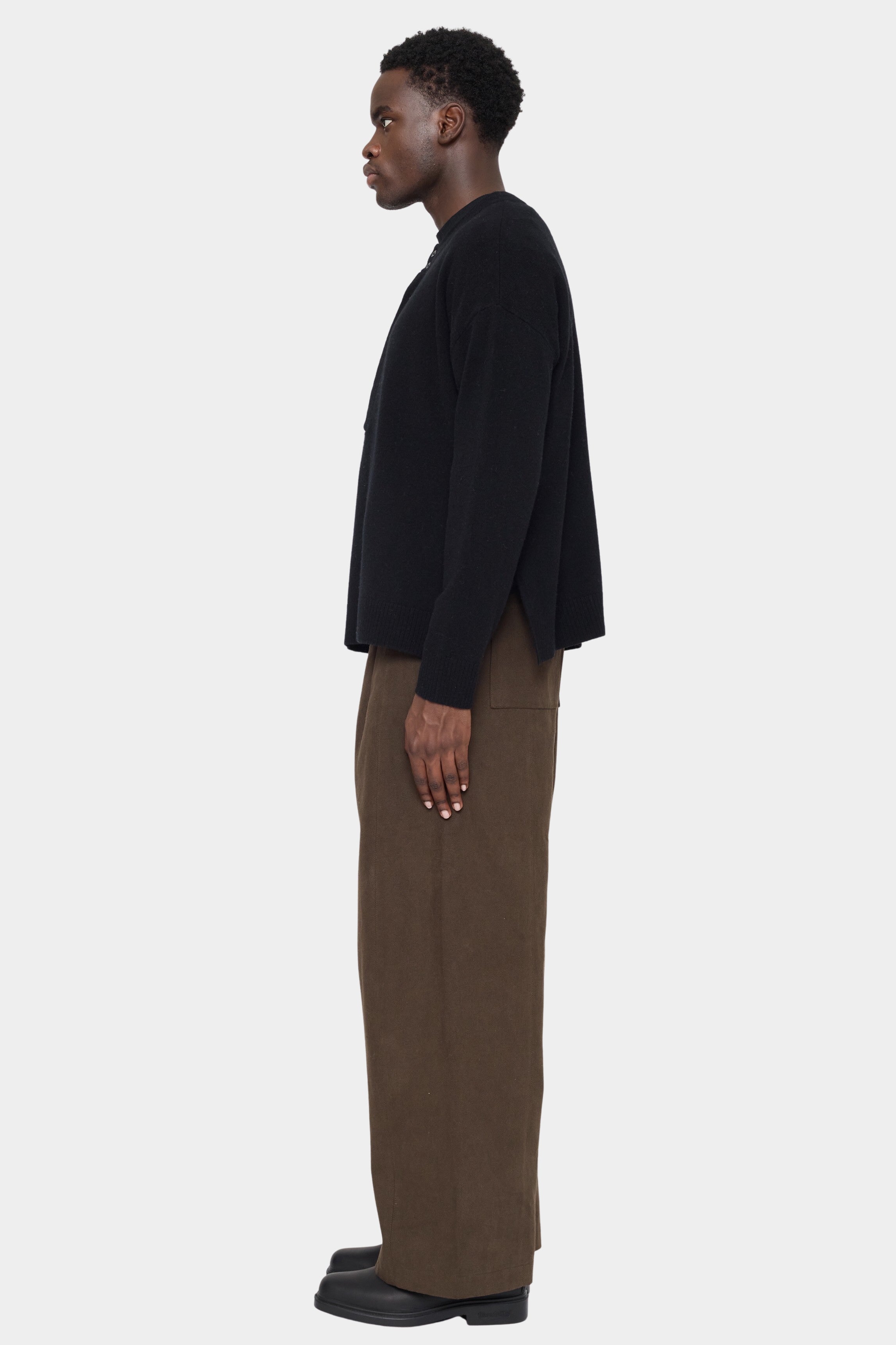Side view of the black Relaxed Pocket Sweater showing the slit at the hem
