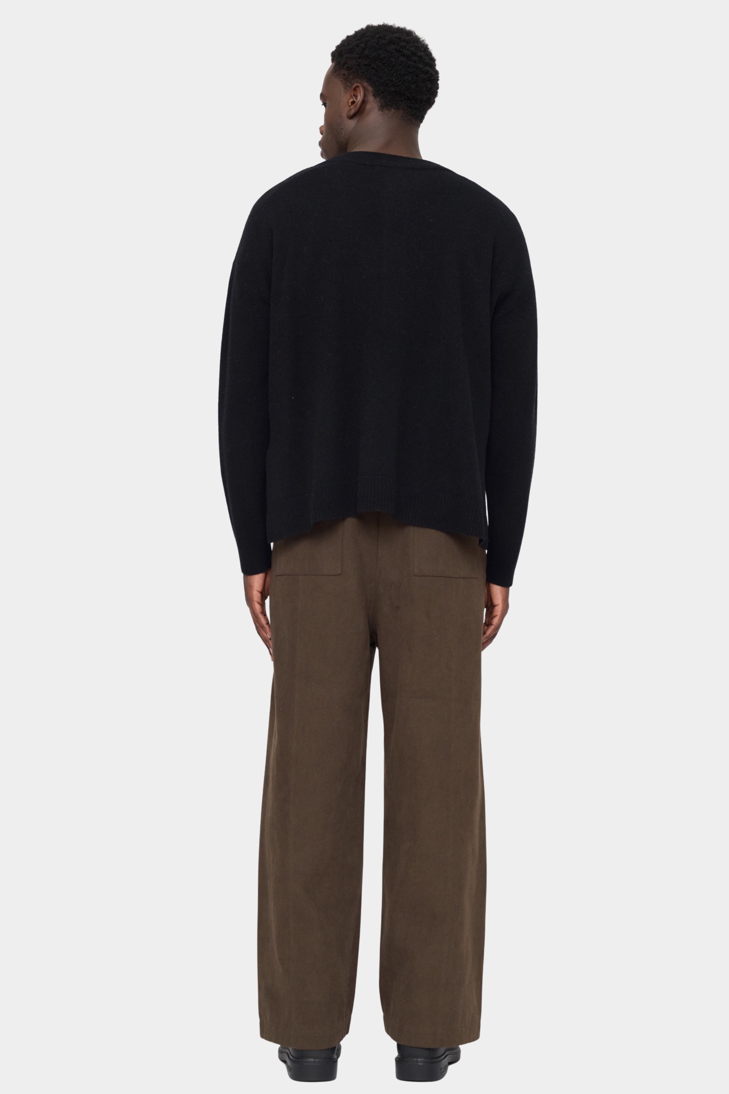 Back view of the black Relaxed Pocket Sweater showing its dropped shoulders and relaxed shape