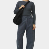 Front view of the black cotton commuter bag worn close to the body with its wide strap across the shoulder