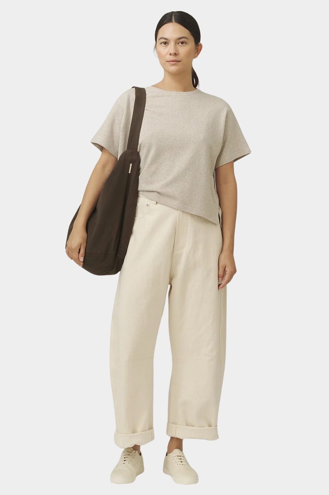 Model carrying the Taupe Brown cotton commuter bag on one shoulder, showing its deep rounded body and wide strap at YUCCA Denver