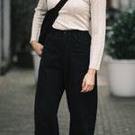 Full front view of the black curved leg work trouser styled with a cream ribbed knit and crossbody bag