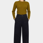 Front view of the black cotton trouser with hands in the side pockets and a relaxed straight leg