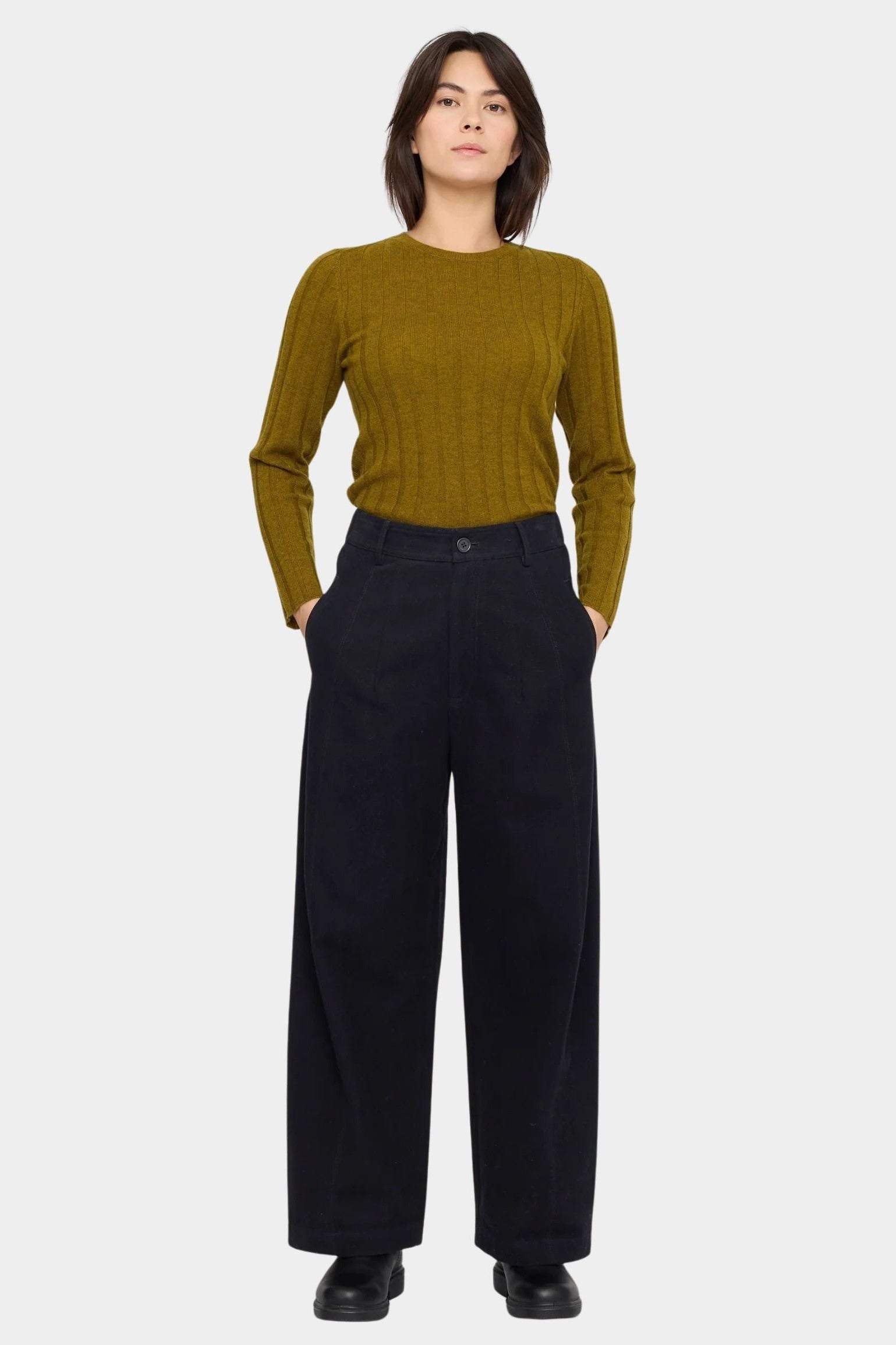 Front view of the black cotton trouser with hands in the side pockets and a relaxed straight leg