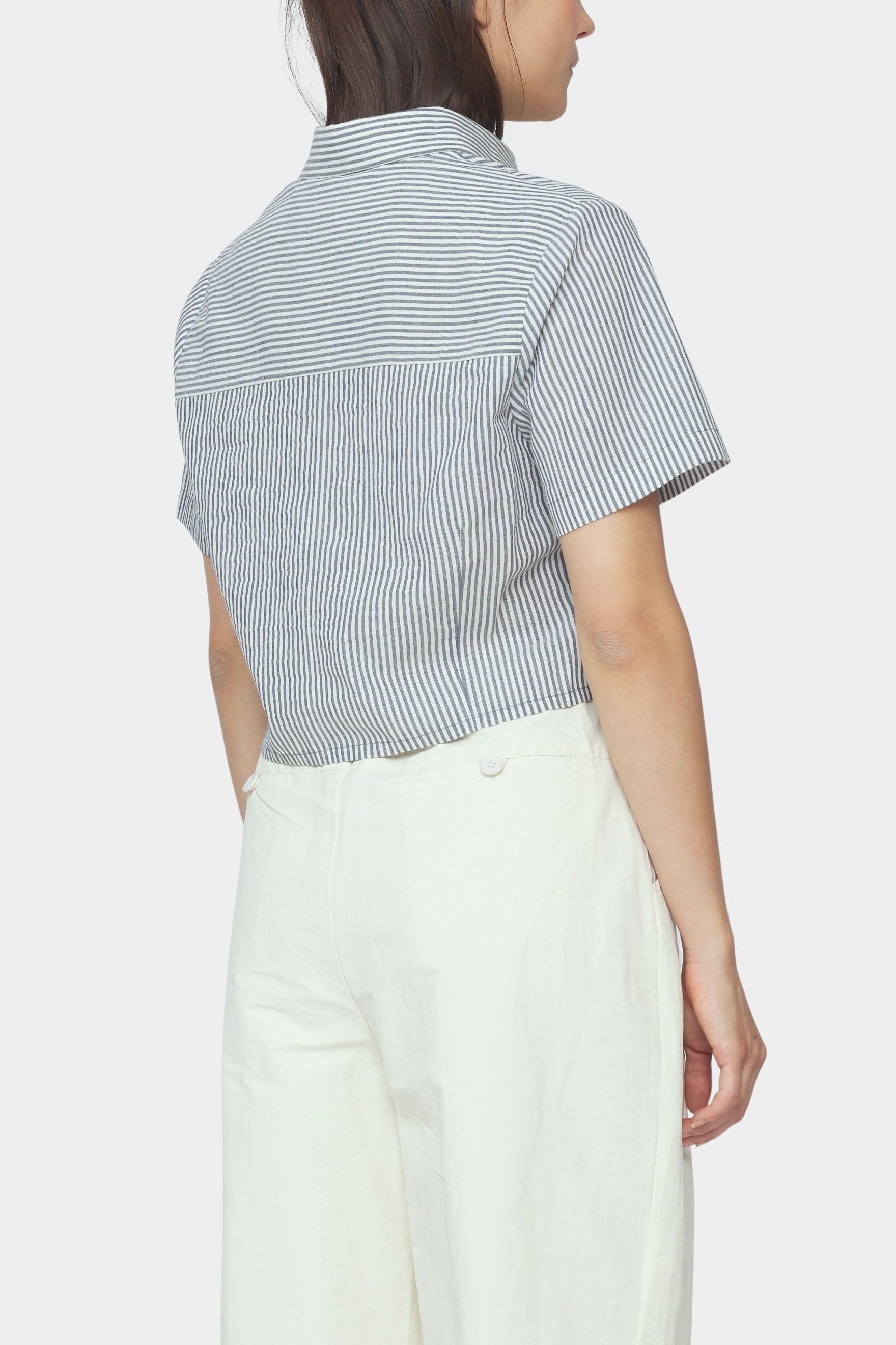 Back and side close up of navy striped cropped shirt with short sleeves and back yoke styled with ivory trousers