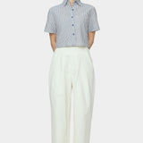 Front view of navy striped cropped button down shirt with short sleeves styled with ivory high waisted trousers