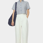 Front view of navy striped cropped shirt with short sleeves and button front styled with ivory trousers and a navy shoulder bag