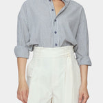 Close up front view of navy striped cotton dolman shirt with rolled sleeves and button placket tucked into ivory trousers