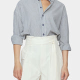 Close up front view of navy striped cotton dolman shirt with rolled sleeves and button placket tucked into ivory trousers
