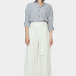 Front view of navy striped dolman shirt tucked into ivory wide leg trousers with rolled sleeves and button front