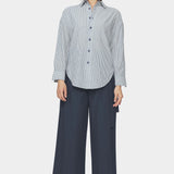 Front view of navy striped dolman shirt with relaxed fit, dropped shoulders, and rounded hem styled with wide leg navy pants