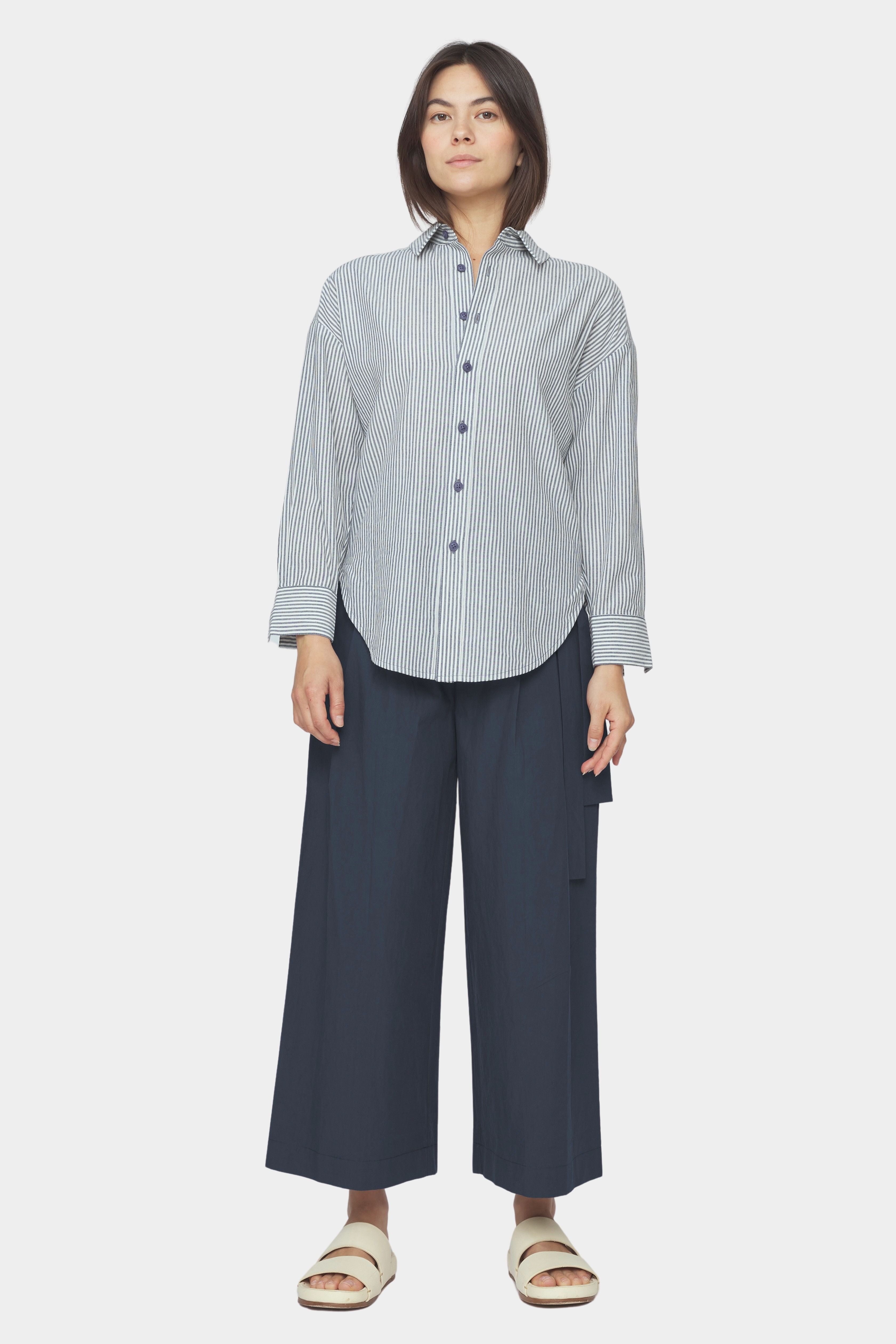 Front view of navy striped dolman shirt with relaxed fit, dropped shoulders, and rounded hem styled with wide leg navy pants