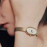 BREDA Jane Tethered gold watch worn on wrist, showing its delicate oval face and jewelry inspired bracelet