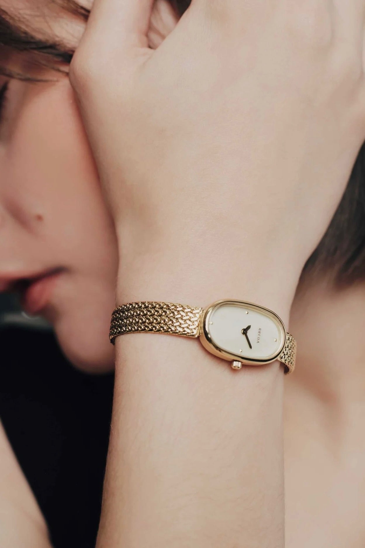 BREDA Jane Tethered gold watch worn on wrist, showing its delicate oval face and jewelry inspired bracelet