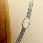 BREDA Jane Tethered two tone watch with silver woven bracelet photographed against a warm cream background