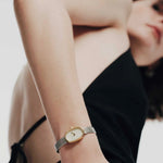 REDA Jane Tethered gold and silver watch worn on wrist with black sleeveless clothing
