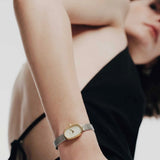 REDA Jane Tethered gold and silver watch worn on wrist with black sleeveless clothing