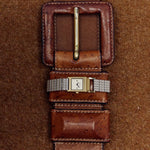 BREDA Revel square face watch styled across a vintage brown leather belt on textured fabric