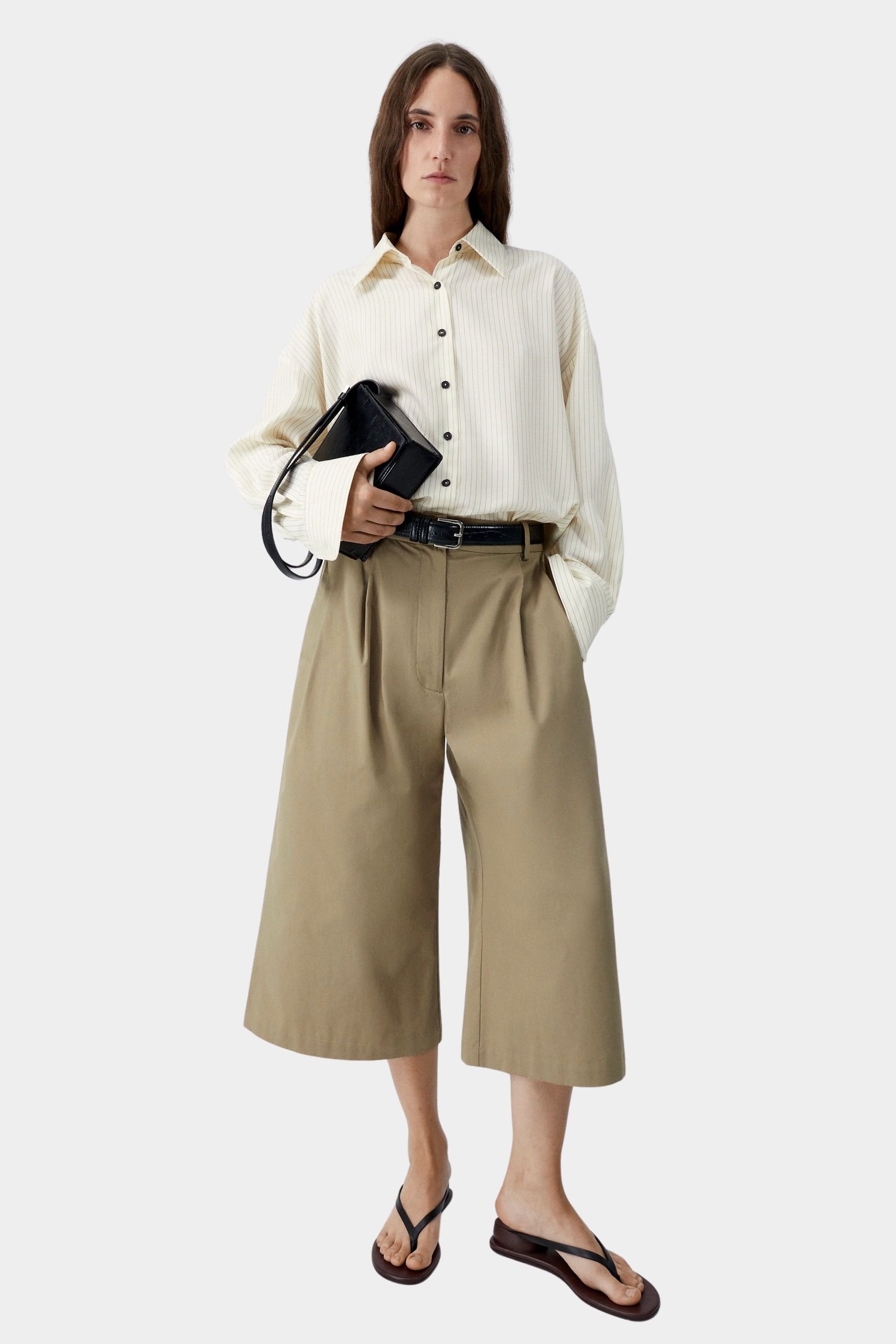 Camel cotton capri pants worn with button-down shirt and sandals