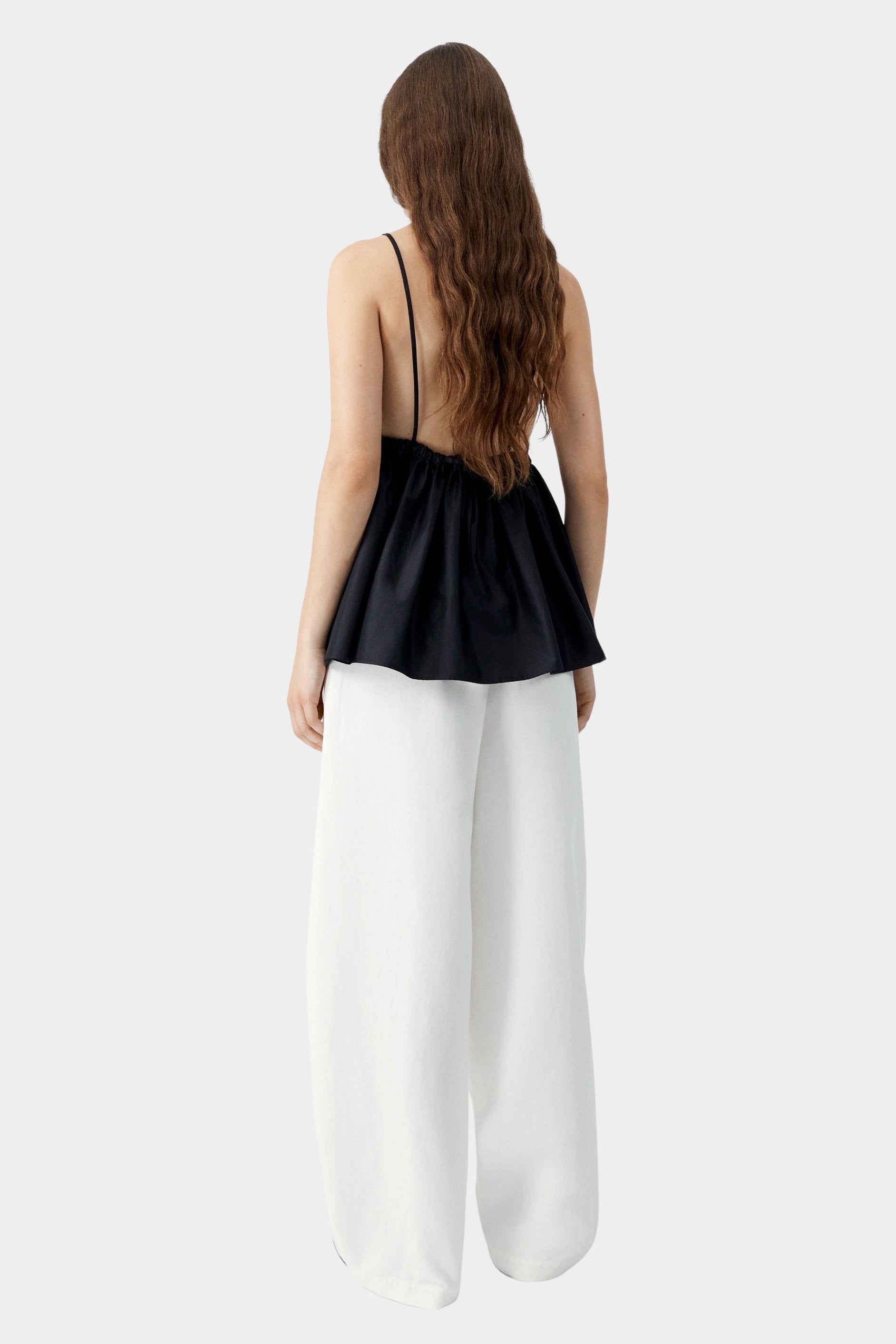 Black camisole top with thin straps, gathered back, and soft drape