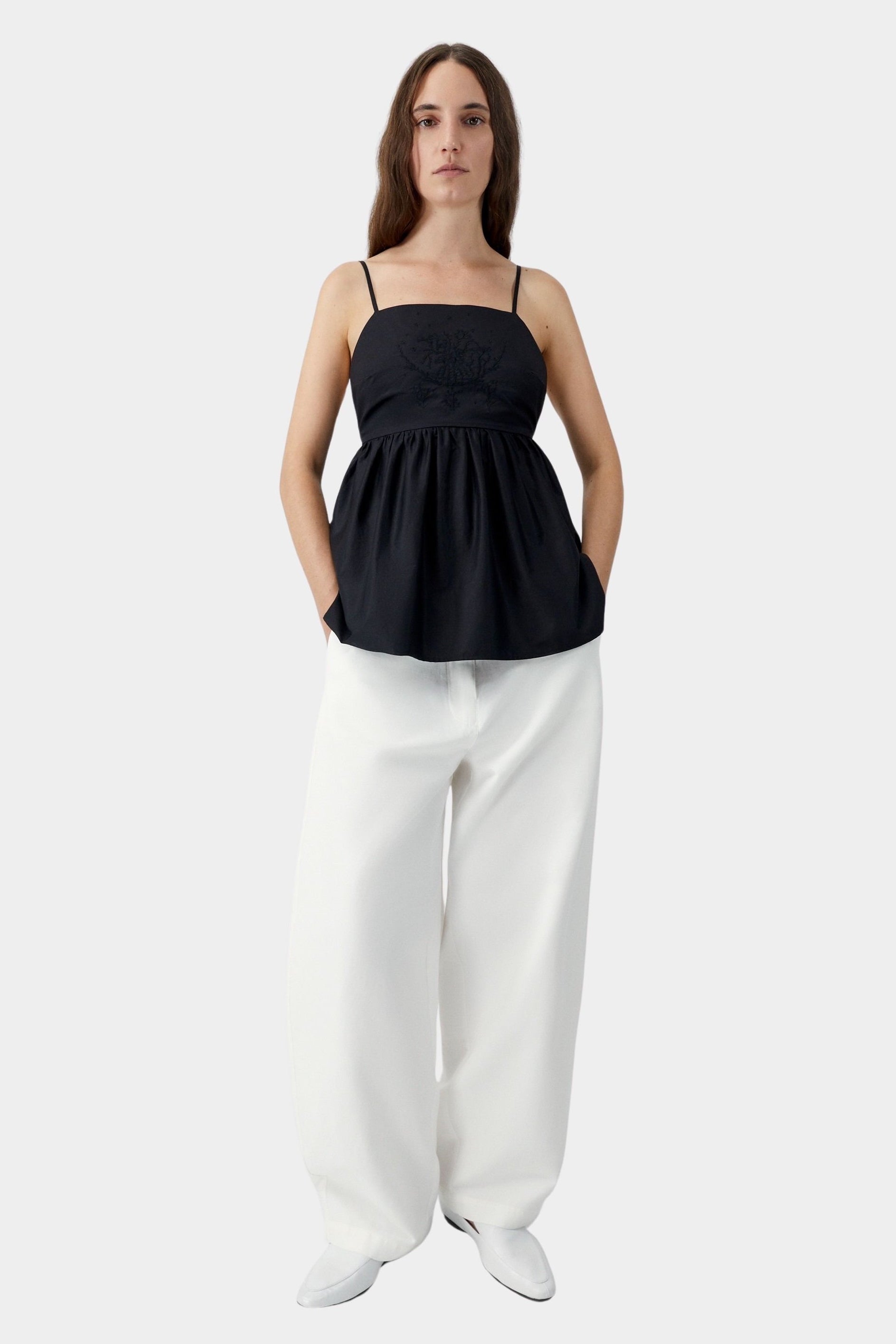Black embroidered camisole top with relaxed silhouette, worn with white trousers