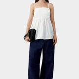 White embroidered camisole top with relaxed fit, worn with dark denim wide leg pants and flats
