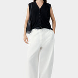White cotton linen curved pants with relaxed fit and subtle taper, worn with black sleeveless top and sandals