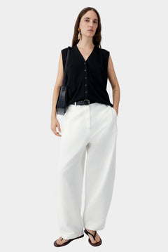 White cotton linen curved pants with relaxed fit and subtle taper, worn with black sleeveless top and sandals