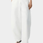 White cotton linen pants with curved leg shape, front button closure, and relaxed tailored fit