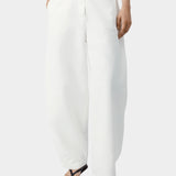 White cotton linen pants with curved leg shape, front button closure, and relaxed tailored fit