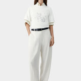 White graphic t-shirt with embroidered lamb motif, layered over shirt and worn with tailored pants